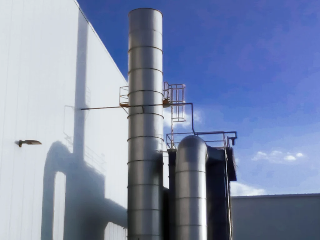 Chimenea y ductería vertical de ventilación industrial en fachada de nave