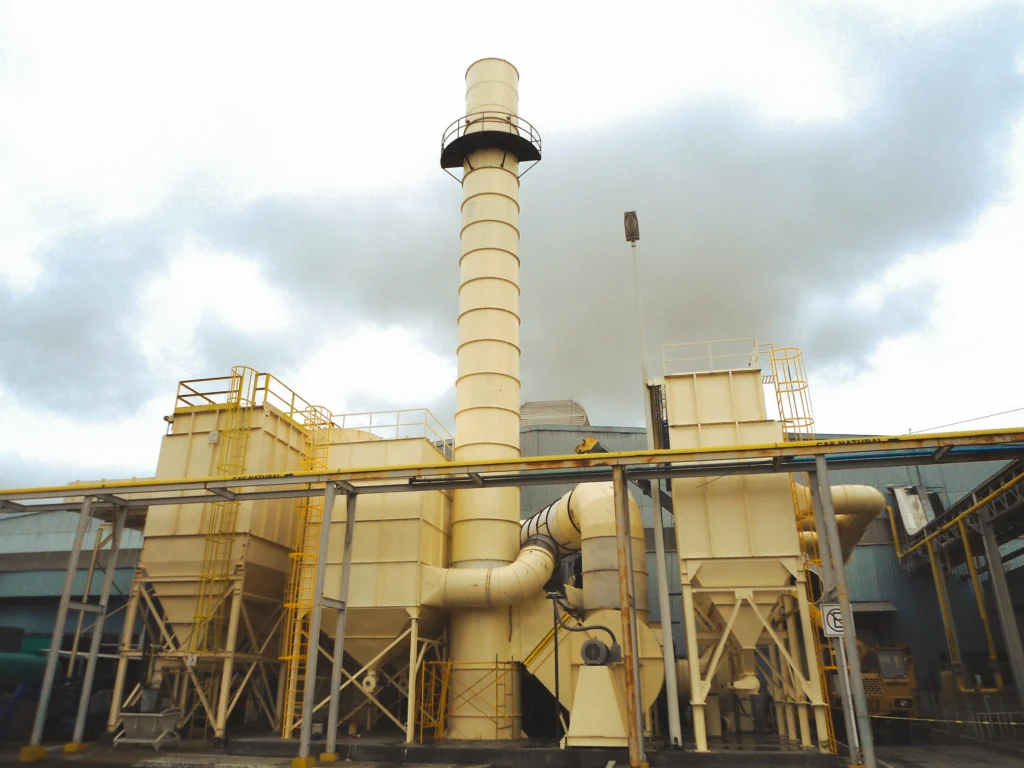 Chimenea industrial con colectores de polvo y ductería en planta de proceso
