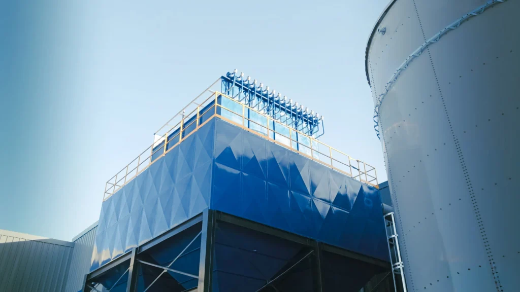 Colector de polvo tipo baghouse azul con pasarela y cabezal de limpieza por pulso junto a silo